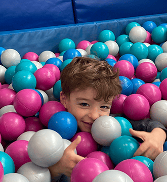 A Little Boy is Playing in a Ball Pit During a Sensory and Motor Therapy Program in Norwood, MA 