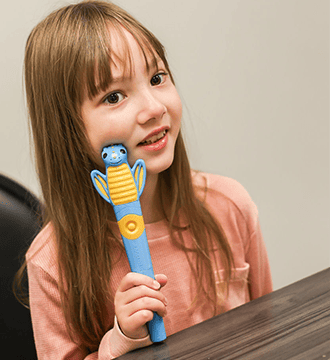 A Girl Is Holding a Feeding Therapy Tool During a Pediatric Feeding Therapy Session in Norwood, MA 