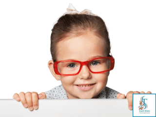 A smiling young girl in red glasses peeking over a ledge